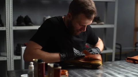 Tracking shot of serious shoemaker in black gloves putting paint on parts of Stock Footage 150069982