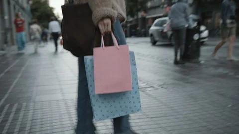 Tracking shot of a shopaholic walking with multiple shopping bags in the city. Video stock 116502299