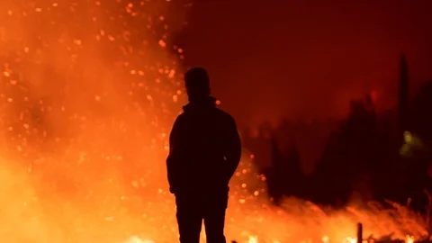Tracking shot of a silhouette man standing in front of Amazon wildfires, Stock Footage