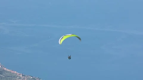 Tracking shot of single man paragliding above lake Garda in Italy in summer Stockbeeldmateriaal 247037184