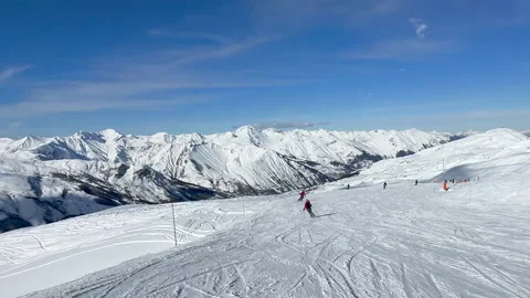 Tracking shot of skiers in red jackets doing carving turns Video stock 233998701