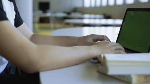 Tracking shot of student working on laptop in library. Chroma key green screen Stock Footage
