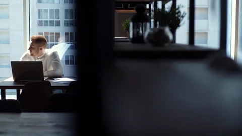 Tracking shot of thoughtful young man is typing on laptop computer at the desk. Stock Footage 130071325
