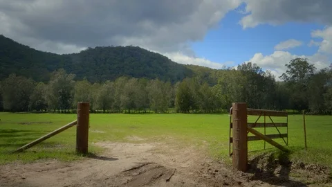Tracking shot through farm gate into lush green field Stock Footage 125063112
