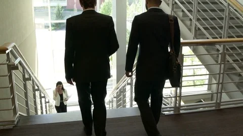 Tracking shot of two businessmen walking down stairs Video stock 76231808