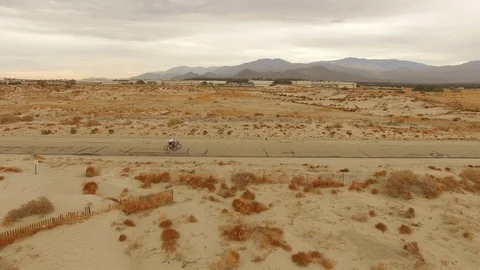 Tracking Shot of Two Road Cyclists Riding in the Desert Stock Footage 90869899