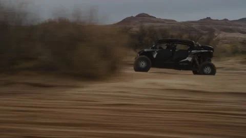 Tracking shot of UTV in Utah driving in red sand wash in desert on cloudy day Stock Footage 234034838