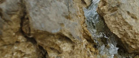 Tracking shot of wave splashing, flowing through rocks in slowmotion Video stock 97898243