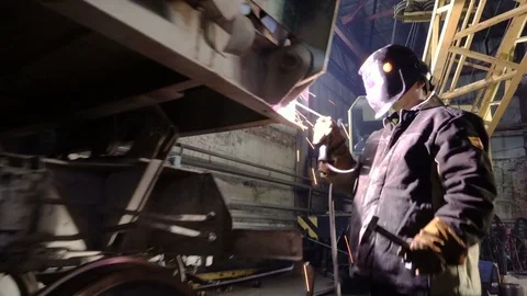 Tracking shot of welder in the protactive mask starting to weld the metal parts Stock Footage 75068394