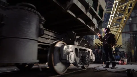 Tracking shot of welder in the protactive mask starting to weld the metal parts Video stock 75068404