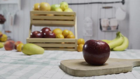 Tracking shot of wet red apple on counter with other fruit behind it Stock Footage 341027455