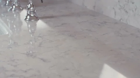 Tracking shot on a white granite surface with chrome faucet Video stock 63499369
