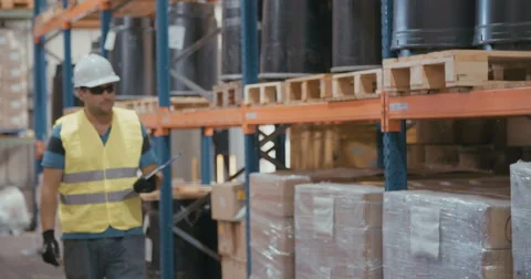 Tracking shot of a worker marking items with a clipboard in a large warehouse Stock-Footage 65039588