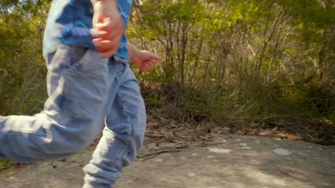 Tracking shot of young boy happily running on a bush track slow motion Stock Footage 130226313