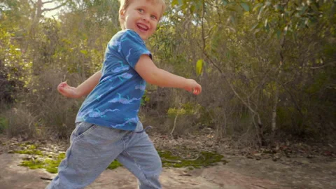 Tracking shot of young boy laughing and running on a bush track slow motion Stock Footage 130226492
