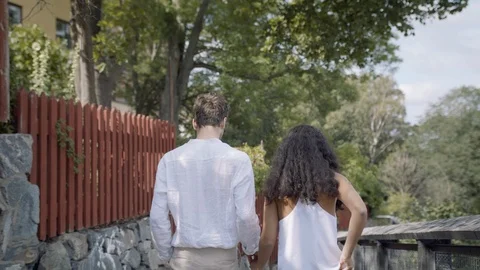 Tracking shot of a young couple walking on a rhustic road in a park. Stockbeeldmateriaal 116136946