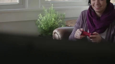 Tracking shot of a young lady gaming on a television in her sunroom Stock Footage 70809768