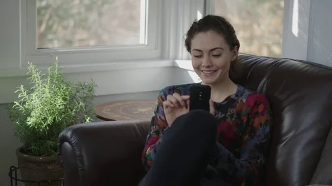 Tracking shot of a young lady scrolling on her cell phone while seated Stock Footage 71326831