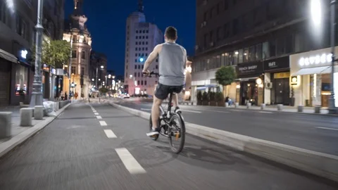 Tracking shot young man biking riding a bike on a city street at night Bucharest Stock Footage 98239726