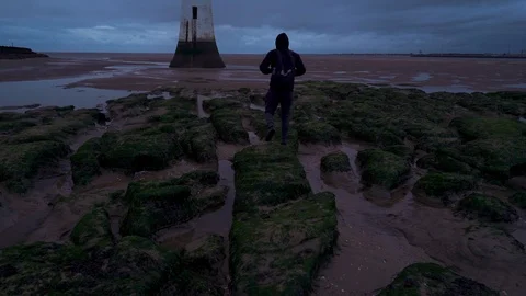 Tracking shot of a young man walking near New Brighton Lighthouse Stock Footage 122287347