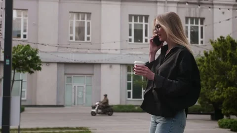 Tracking side view slow motion shot of young woman with takeaway coffee cup Video stock 242713341