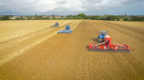 Tracking slow motion aerial drone shot of tractors ploughing Stock-Footage 59864622