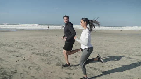 Tracking, Slowmotion shot of Young Couple Jogging on Beach Stock Footage 233386608