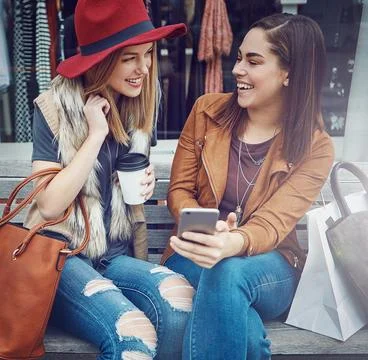 Tracking their savings via an app. two young girlfriends sending text messages Stock Photos