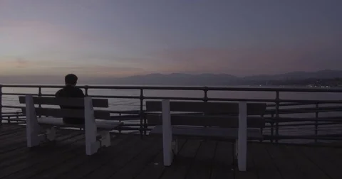 Tracking Towards Man Sitting On A Bench At The Pier At Dusk Stock Footage 85351701