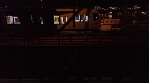 Tracking train along bridge while flying sideways at night looking into Stock Footage 117977759