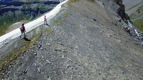 Tracking two people running on top of a ridge in the swiss mountains alps Stock Footage 128947545