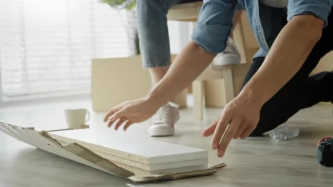 Tracking video of couple checking manual before installing furniture Stock Footage 132705327