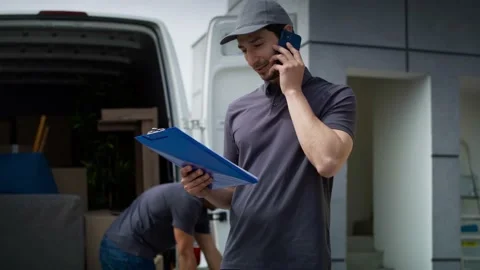 Tracking video of delivery man calling a customer. Stock Footage 155730127