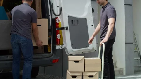 Tracking video of delivery men loading parcels onto a delivery truck. Stock Footage 155730131