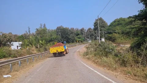 Tracking video of tractor loaded with soil moving along road in rural setti.. Stock Footage 336365878