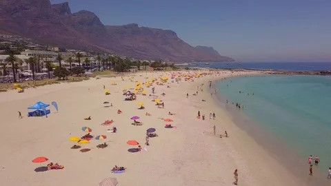 A tracking view over umbrellas and bathers along the coastline of Camps Bay. Video stock 83336970