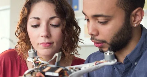 Tracking Young Attractive Man and Woman Wiring The Inside Of A Robot In A Stock-Footage 82677311