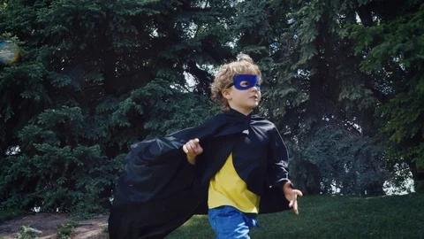 Tracking with young boy playing superhero as he notices something and chases it Stock Footage 127547498