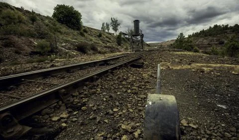 Tracks of the train next to the handle surrounded by trees under a clouded sk Photos