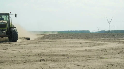 A tractor with an agricultural machine processes the soil, a lot of dust rises 库存影片 89777345