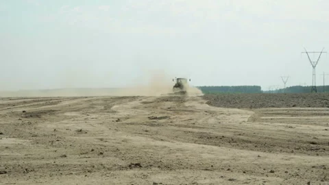 A tractor with an agricultural machine processes the soil, a lot of dust rises 库存影片 89778228