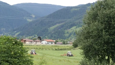 A tractor in an alpine meadow cutting green grass to make nutritious silage Stock Footage 158048368