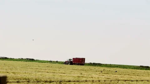 Tractor and an empty trailer on a farm track during hay-making season Stock Footage 43671842