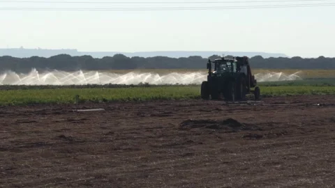 Tractor and Irrigation System Watering Farmland With Sprinklers Across Fields Stock Footage 346765005