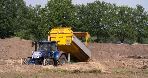 Tractor and tipping trailer dumping yellow sand at a construction site Stock Footage 109569379