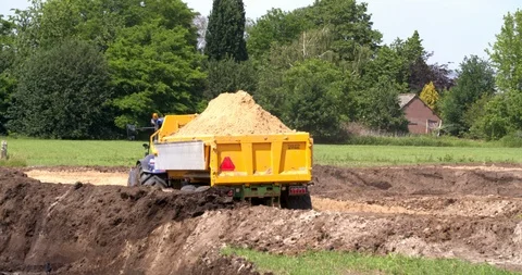 Tractor and tipping trailer dumping yellow sand at a construction site Vídeo Stock 109569604