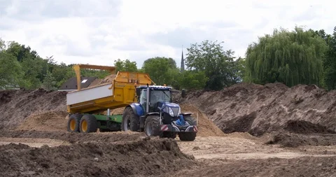Tractor and tipping trailer dumping yellow sand at a construction site Stock Footage 109831296