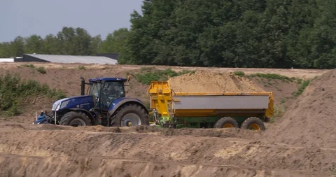 Tractor and tipping trailer transporting yellow sand at construction site Stock Footage 109573427