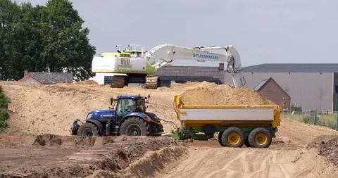 Tractor and tipping trailer transporting yellow sand at construction site Stock Footage 109573428