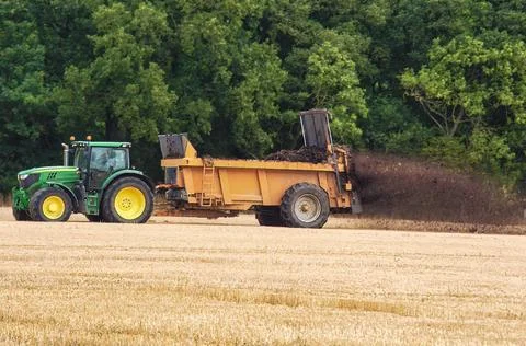 Tractor and trailer spreading manure in a field Stock Photos